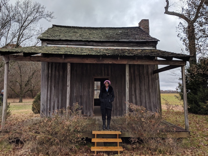 a woman standing in front of a wood house